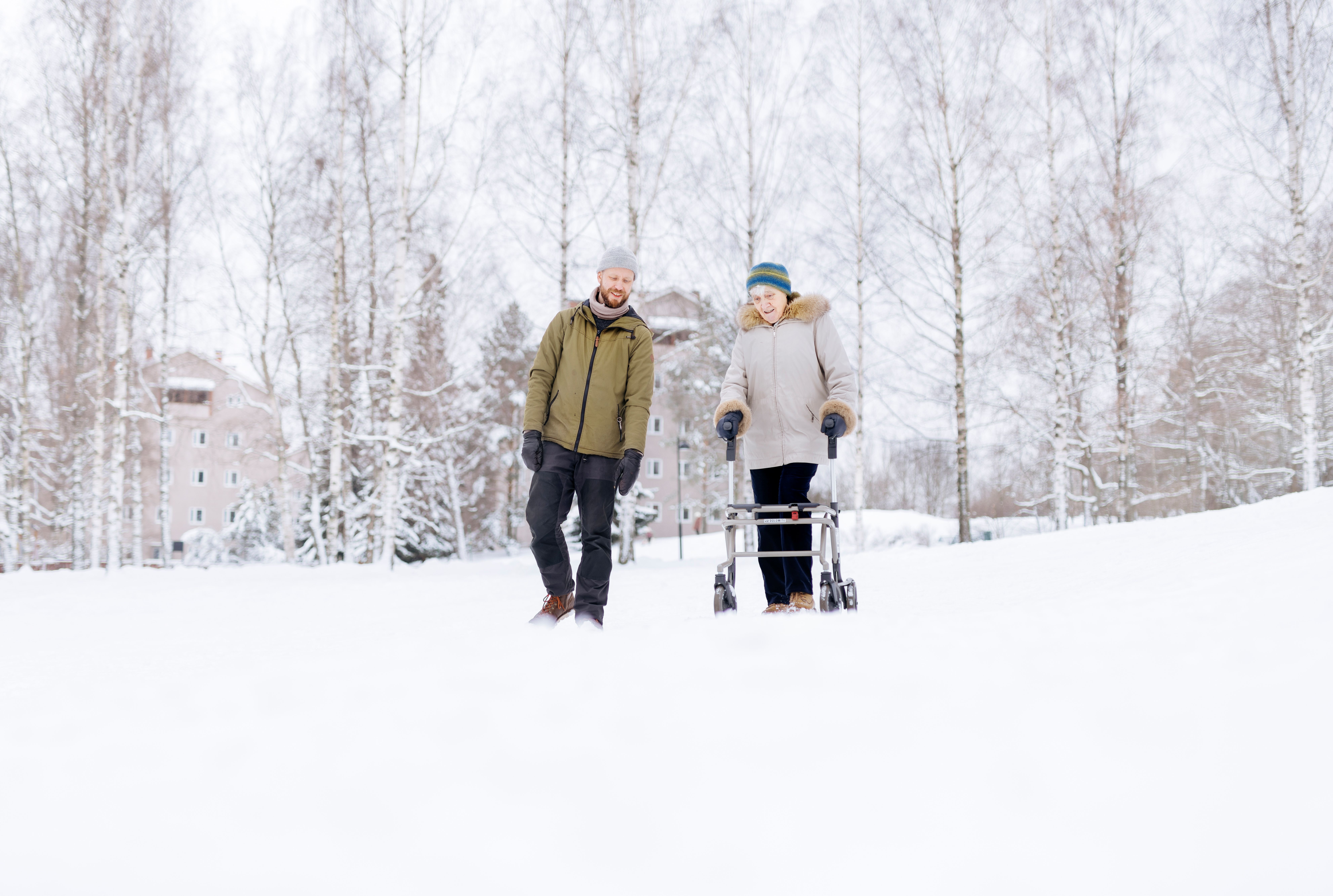 Mies ja mummo kävelevät lumisessa maisemassa.